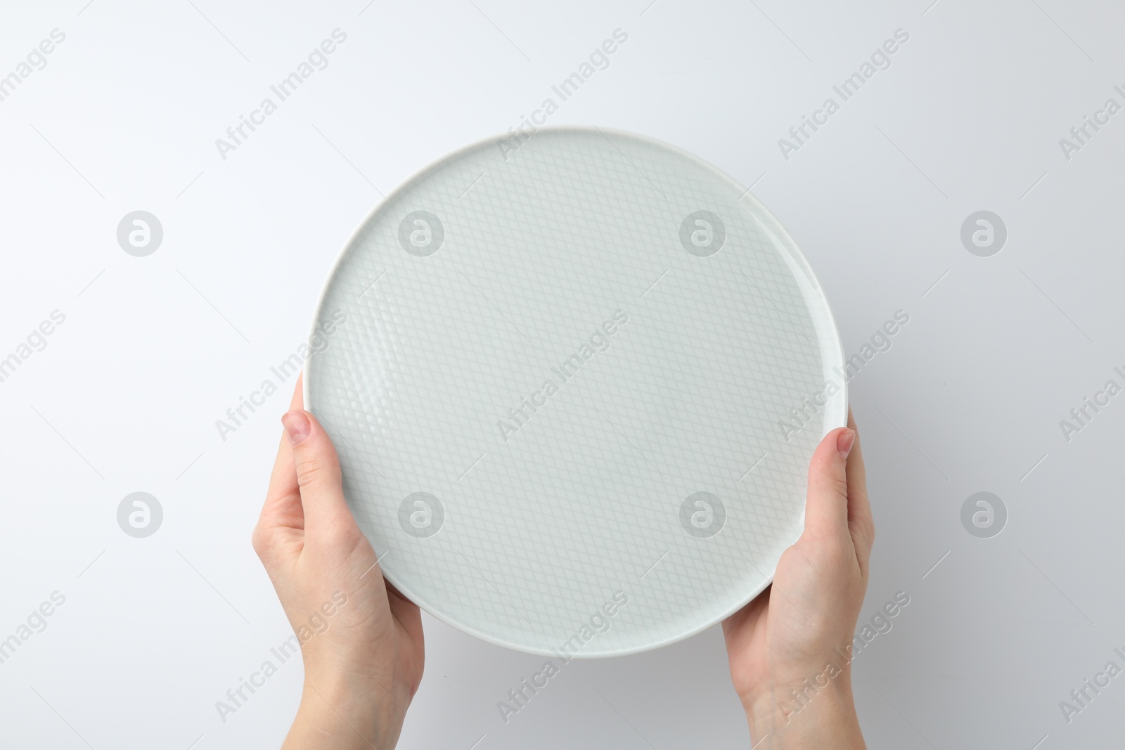 Photo of Woman with empty ceramic plate on white background, top view