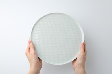 Woman with empty ceramic plate on white background, top view