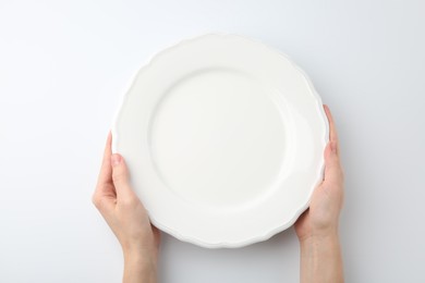 Photo of Woman with empty ceramic plate on white background, top view