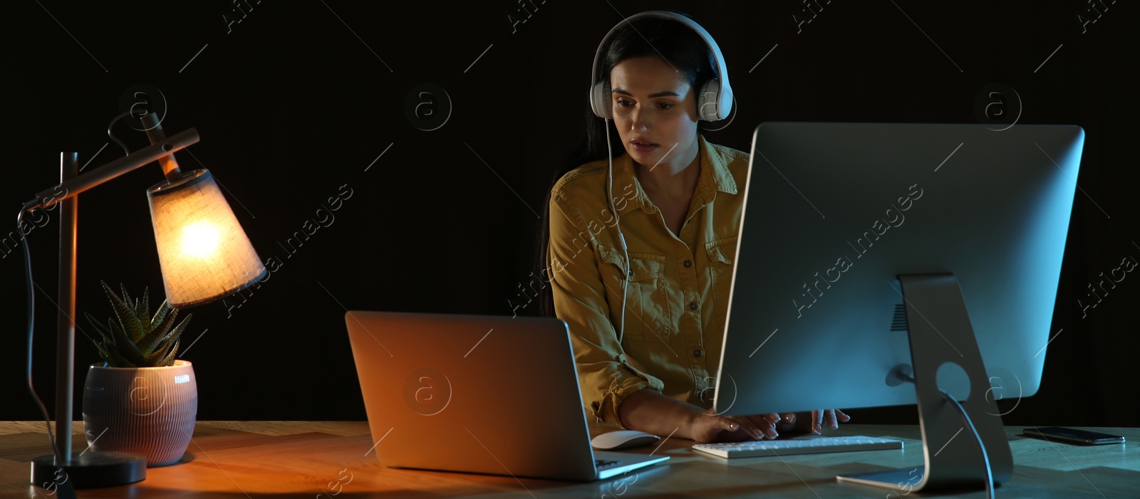 Image of Programmer with headphones working in office at night. Banner design