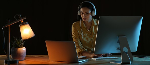 Programmer with headphones working in office at night. Banner design