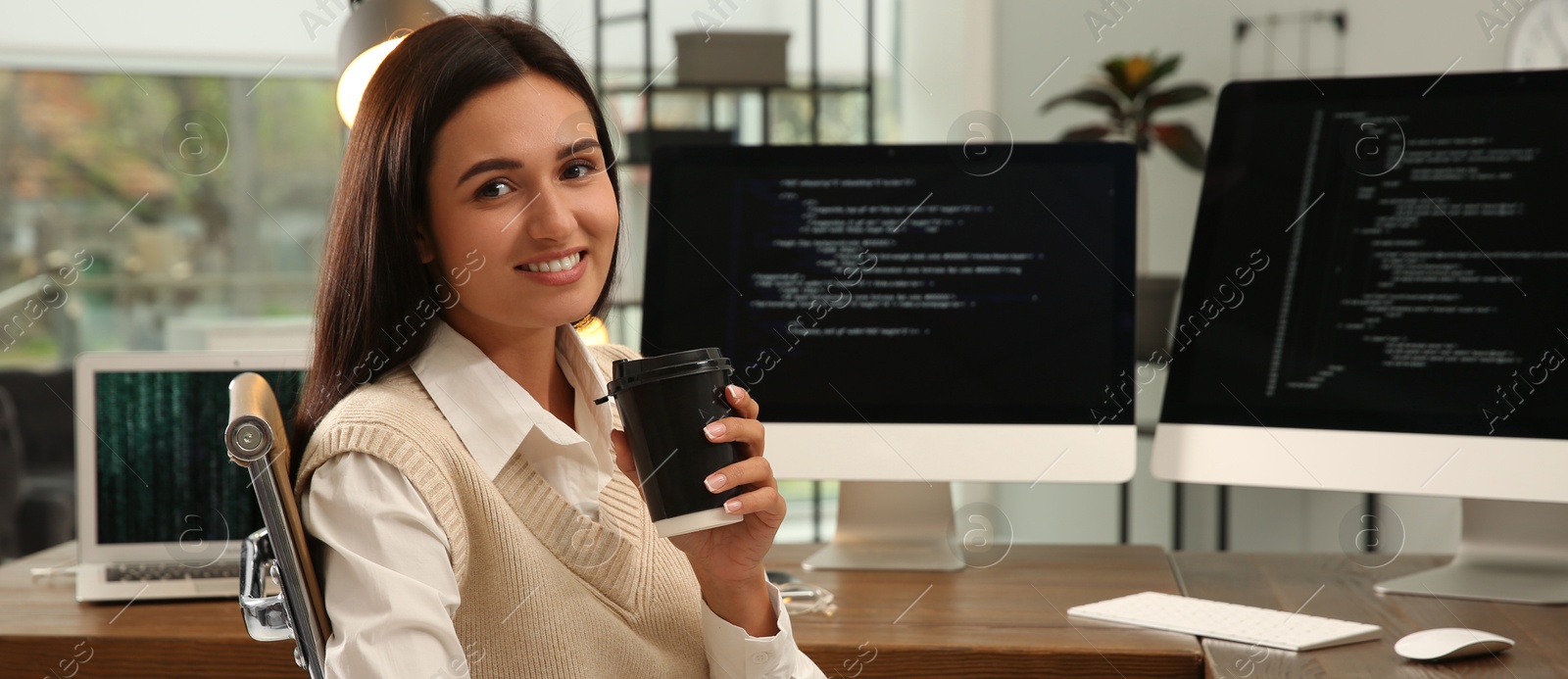 Image of Programmer with cup of coffee working at desk in office. Banner design