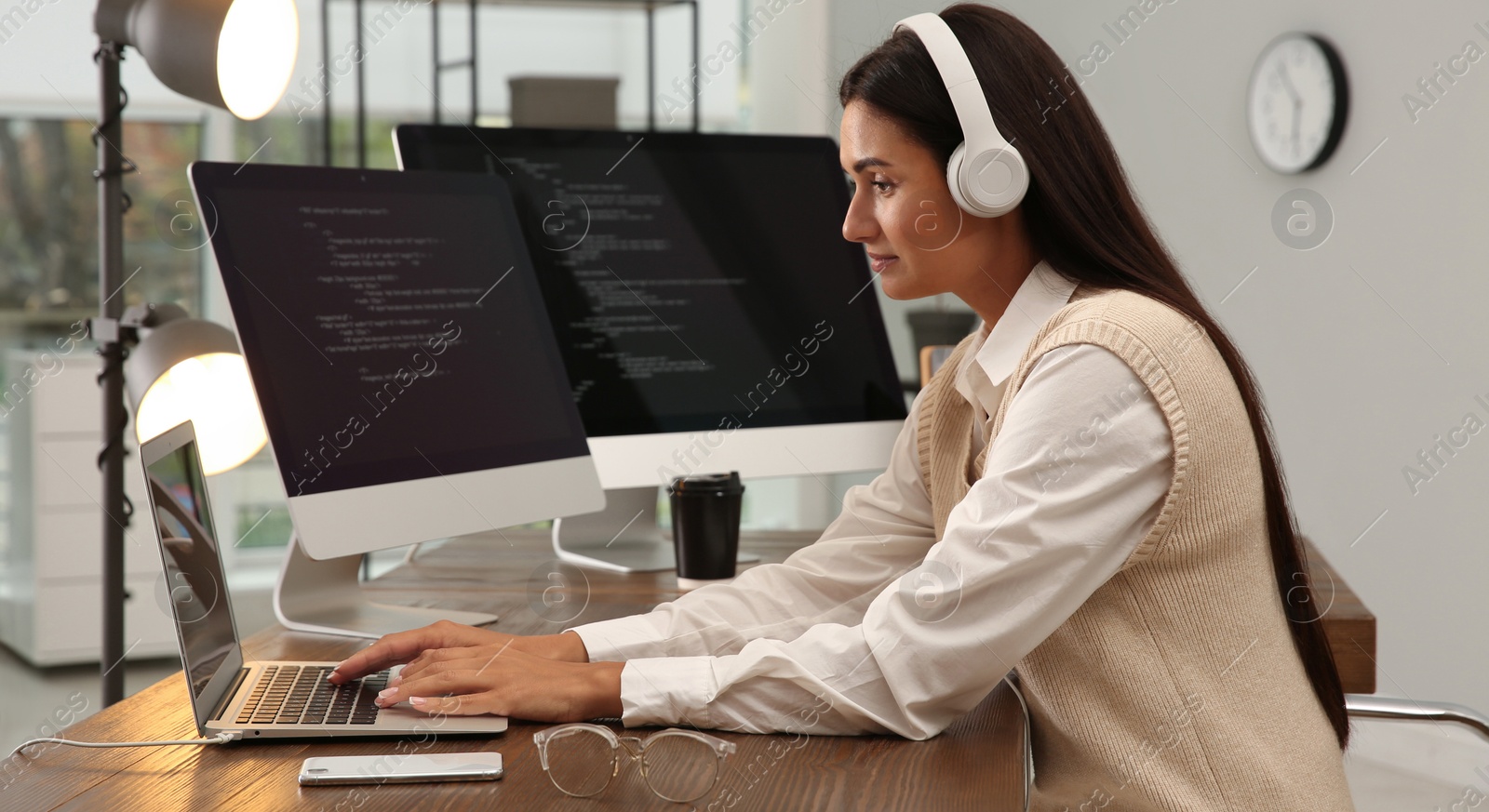 Image of Programmer with headphones working at desk in office. Banner design