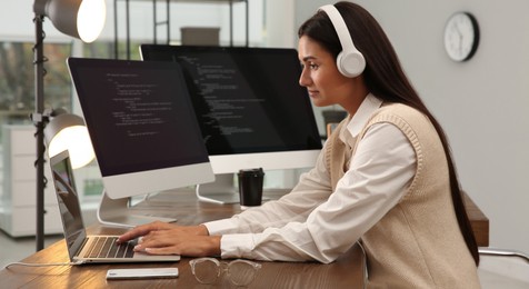 Programmer with headphones working at desk in office. Banner design