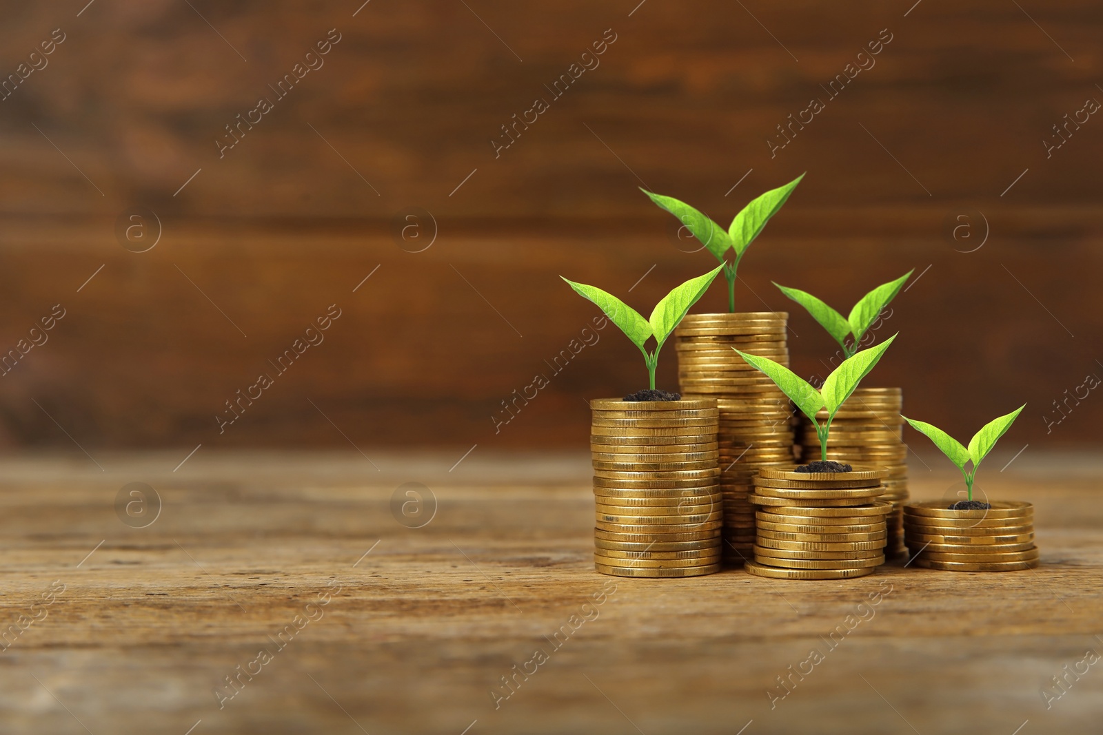 Image of Stacked coins with green seedlings on wooden background, space for text