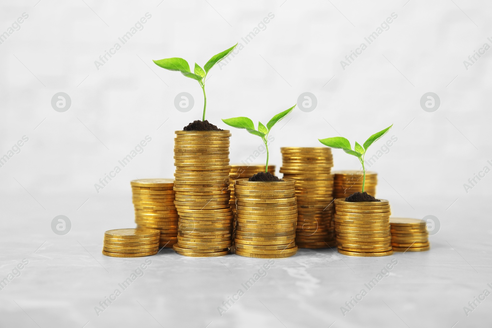 Image of Stacked coins with green seedlings on white background