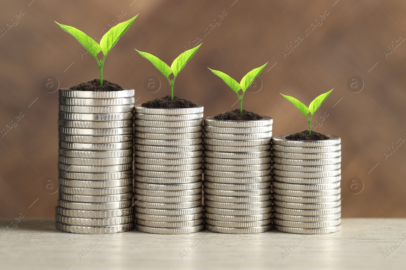 Image of Stacked coins with green seedlings on white table