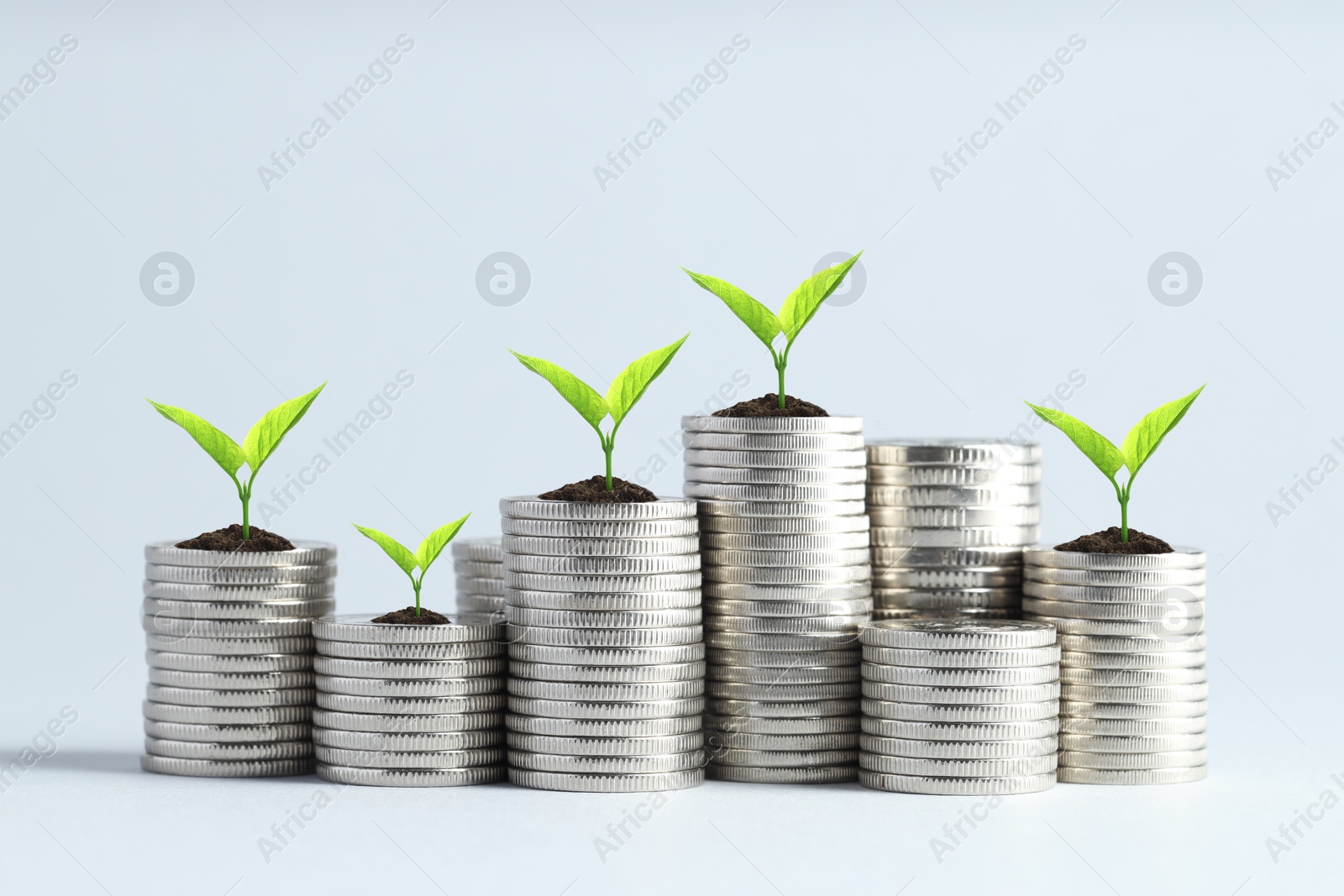 Image of Stacked coins with green seedlings on white background