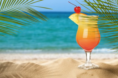 Image of Summer beach with delicious Tequila Sunrise cocktail, palm leaves and golden sand, space for text