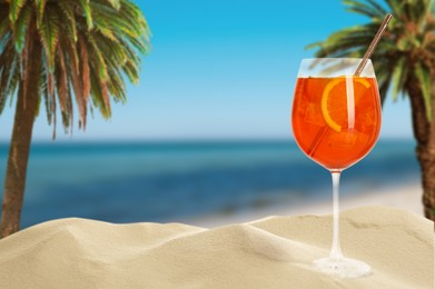 Image of Summer beach with delicious Aperol Spritz cocktail, palm trees and golden sand, space for text