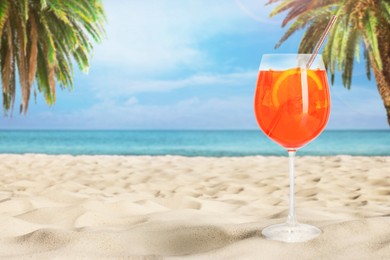 Image of Summer beach with delicious Aperol Spritz cocktail, palm trees and golden sand, space for text