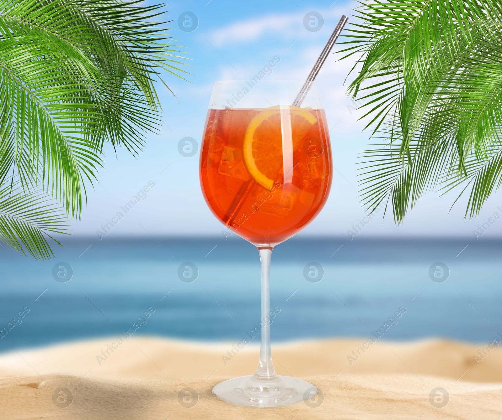 Image of Summer beach with delicious Aperol Spritz cocktail, palm leaves and golden sand