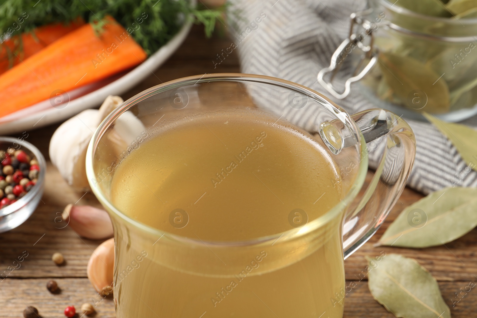 Photo of Hot delicious bouillon in glass cup on table, closeup