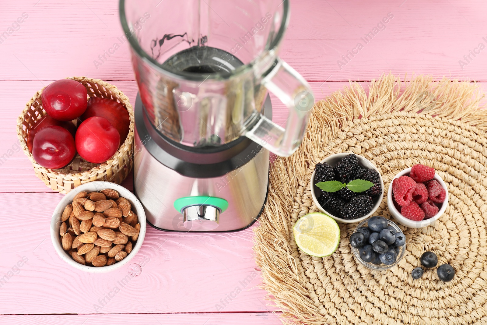 Photo of Blender and fresh ingredients on pink wooden table, above view