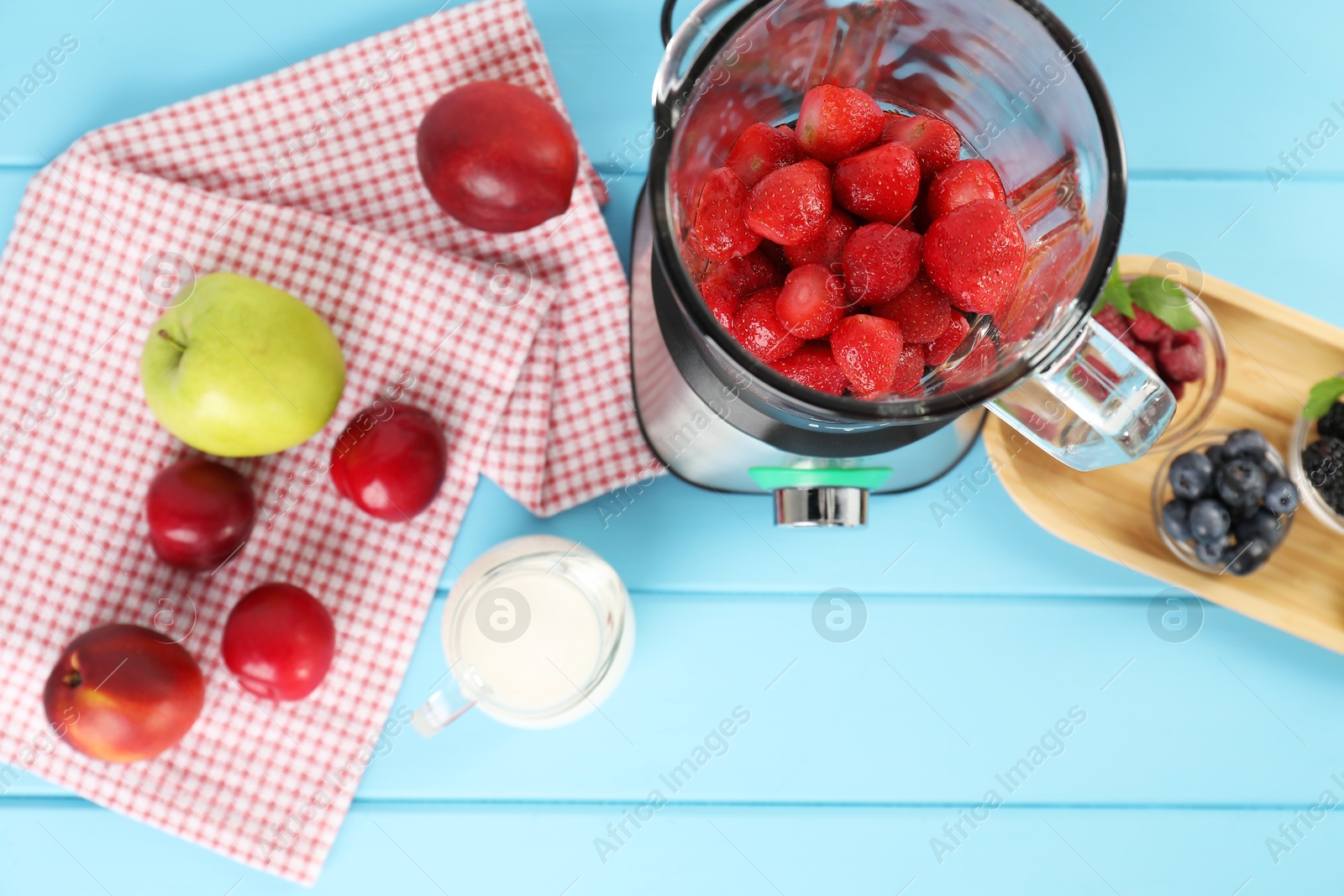 Photo of Blender and fresh ingredients on light blue wooden table, top view