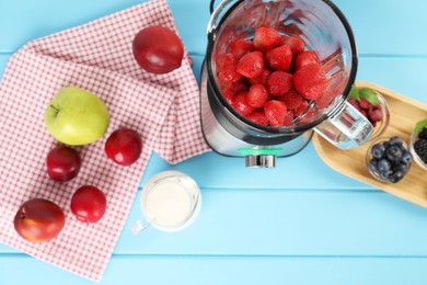 Photo of Blender and fresh ingredients on light blue wooden table, top view