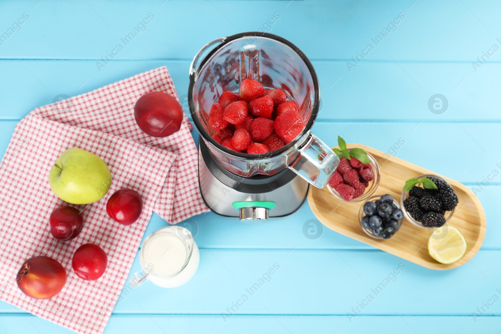 Photo of Blender and fresh ingredients on light blue wooden table, top view