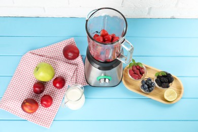 Blender and fresh ingredients on light blue wooden table