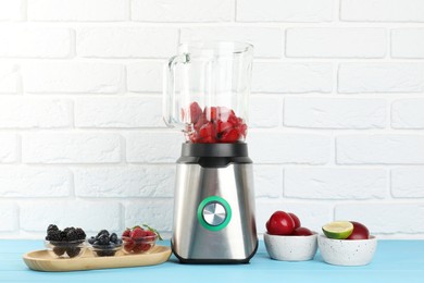 Blender and fresh ingredients on light blue wooden table