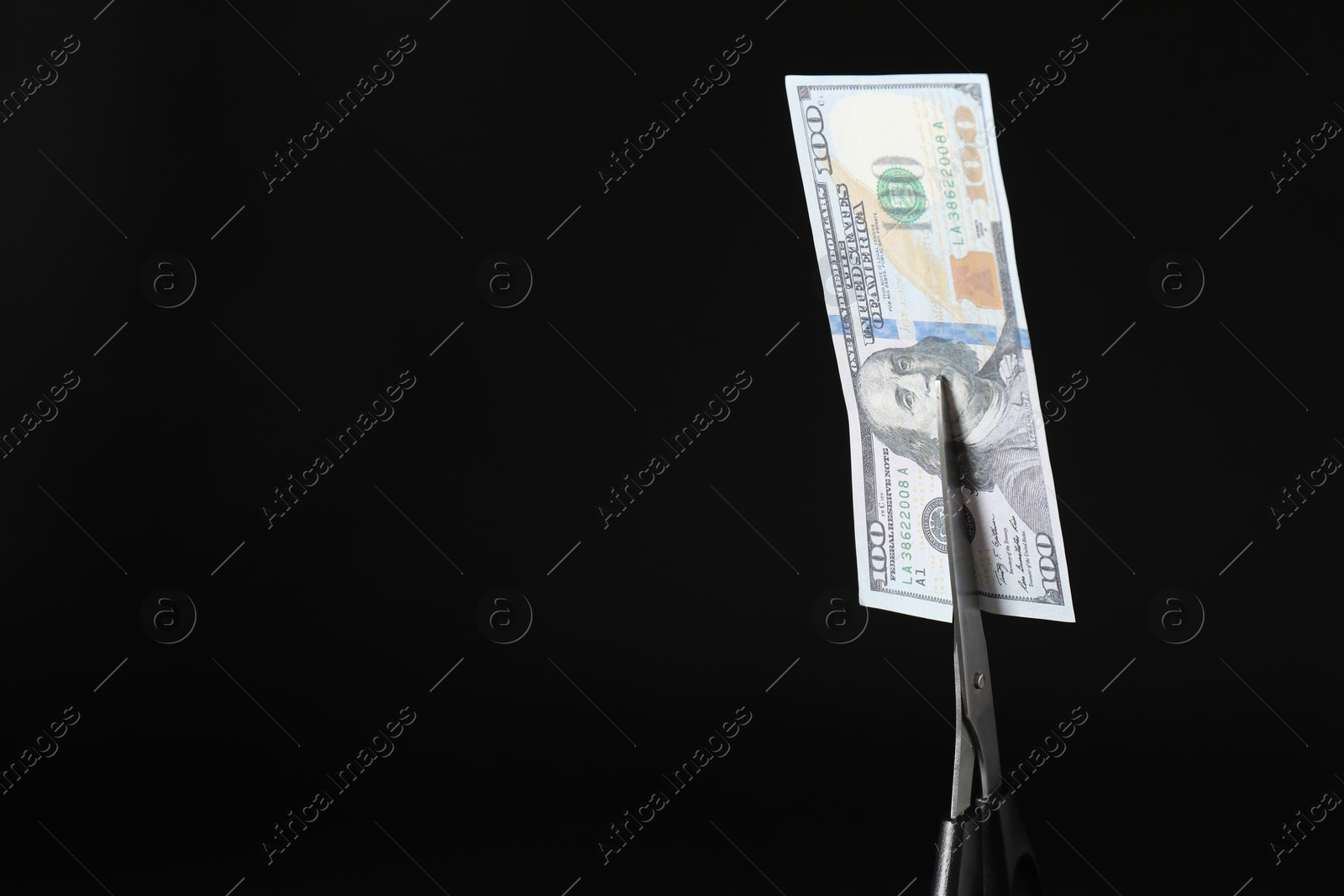 Photo of Budgeting. Cutting dollar banknote with scissors on black background, closeup