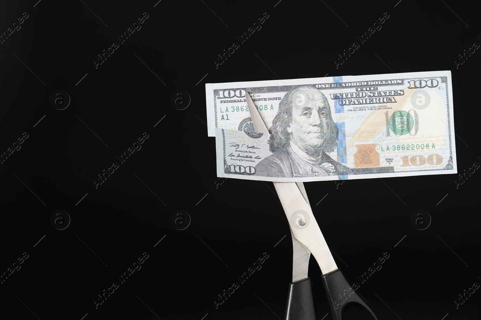 Photo of Budgeting. Cutting dollar banknote with scissors on black background, closeup