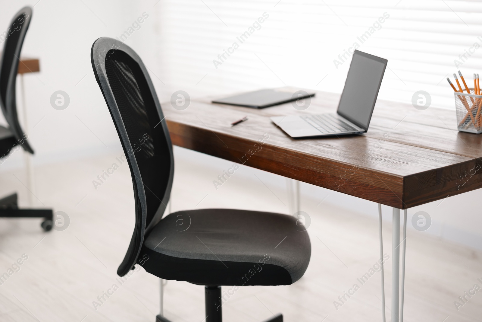 Photo of Black chair, laptop and desk in office