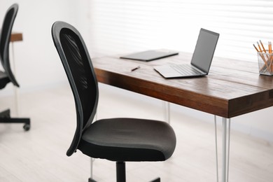 Black chair, laptop and desk in office