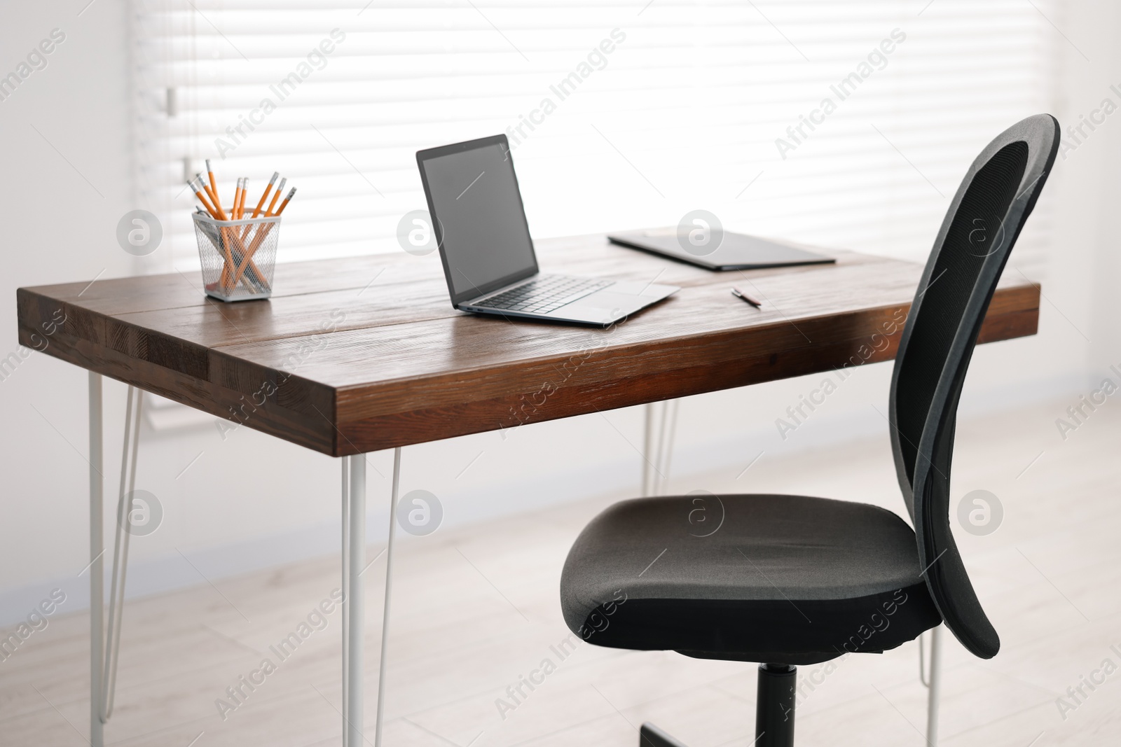 Photo of Black chair, laptop and desk in office