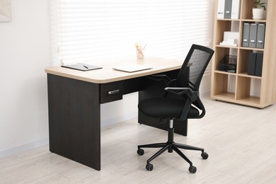 Black chair, laptop and desk in office