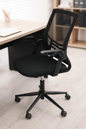 Black chair, laptop and desk in office