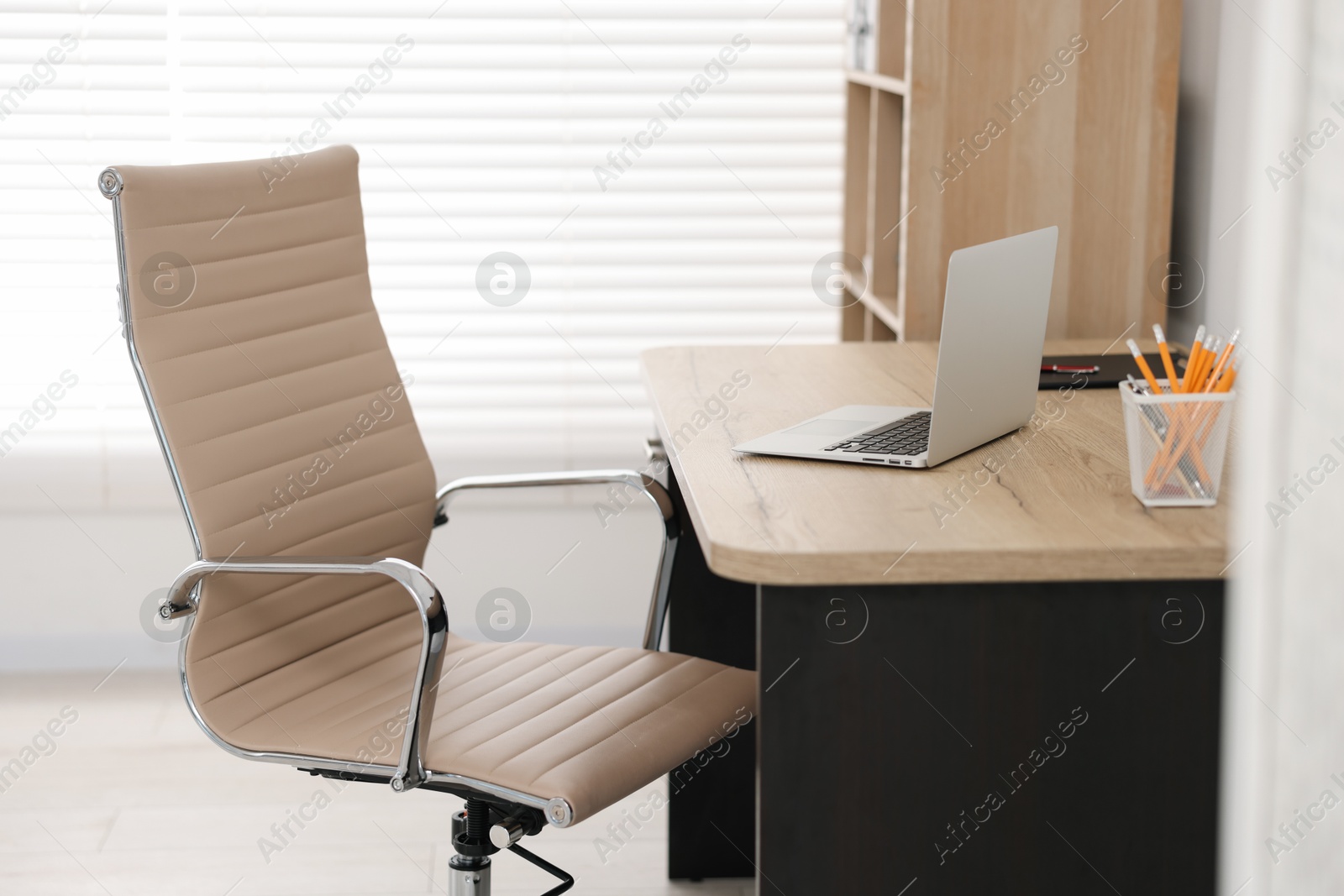 Photo of Beige leather chair, laptop and desk in office