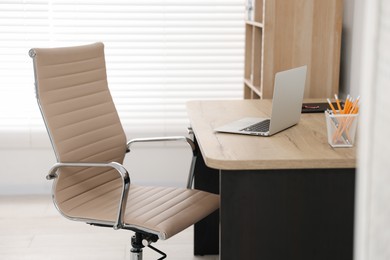 Photo of Beige leather chair, laptop and desk in office