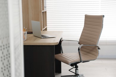 Photo of Beige leather chair, laptop and desk in office