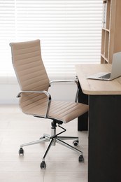 Photo of Beige leather chair, laptop and desk in office