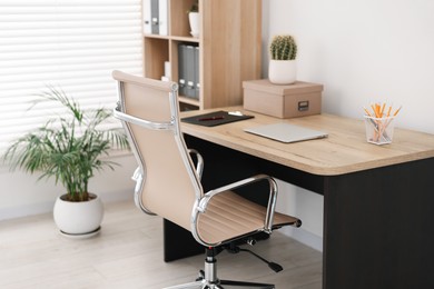 Beige leather chair, laptop and desk in office