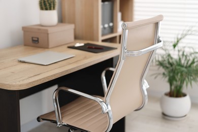 Photo of Beige leather chair, laptop and desk in office