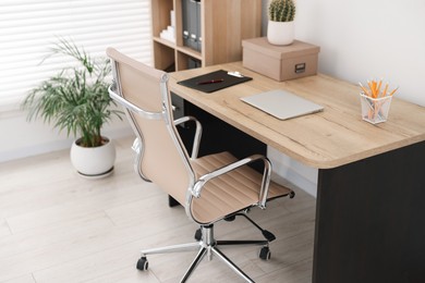 Beige leather chair, laptop and desk in office, above view