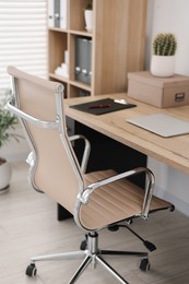 Beige leather chair, laptop and desk in office, above view