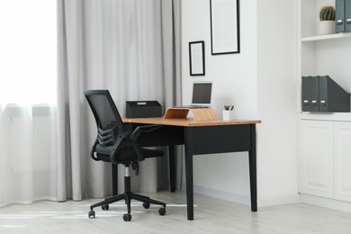 Black chair, laptop and desk in office