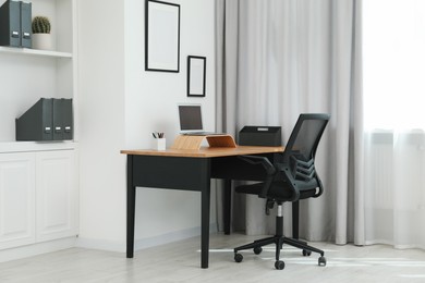 Black chair, laptop and desk in office