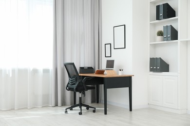 Black chair, laptop and desk in office