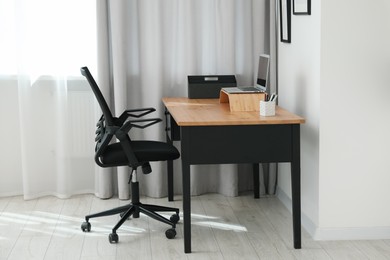 Black chair, laptop and desk in office