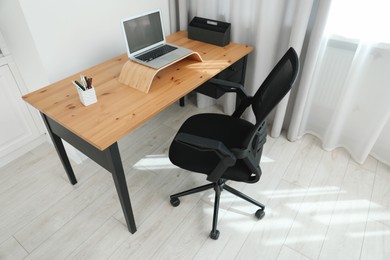 Photo of Black chair, laptop and desk in office, above view