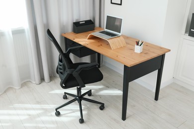 Black chair, laptop and desk in office