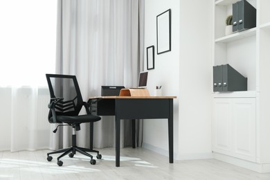 Photo of Black chair, laptop and desk in office