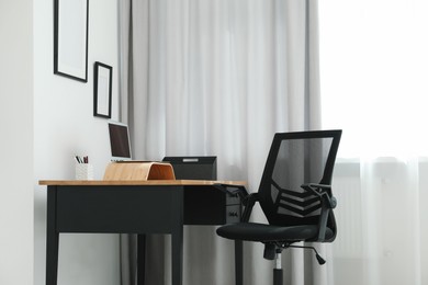 Photo of Black chair, laptop and desk in office