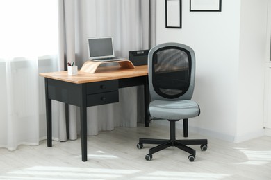 Photo of Grey chair, laptop and desk in office