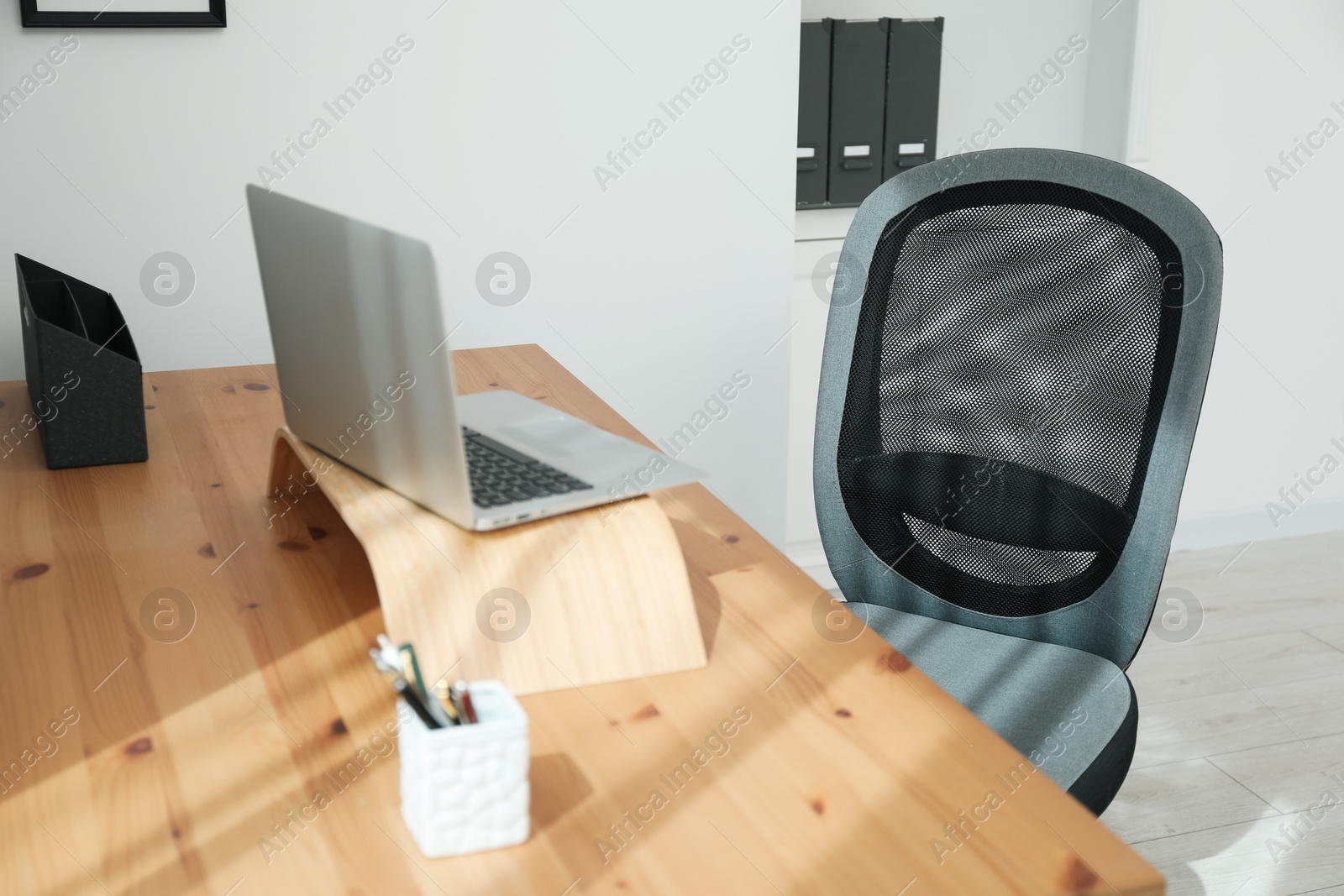 Photo of Grey chair, laptop and desk in office, closeup