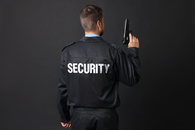 Security guard in uniform with gun on black background, back view