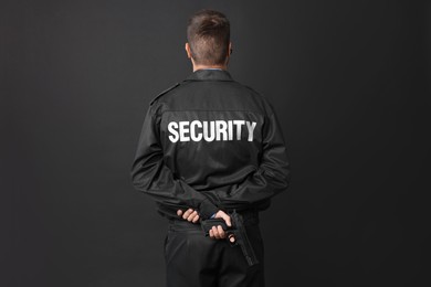 Security guard in uniform with gun on black background, back view